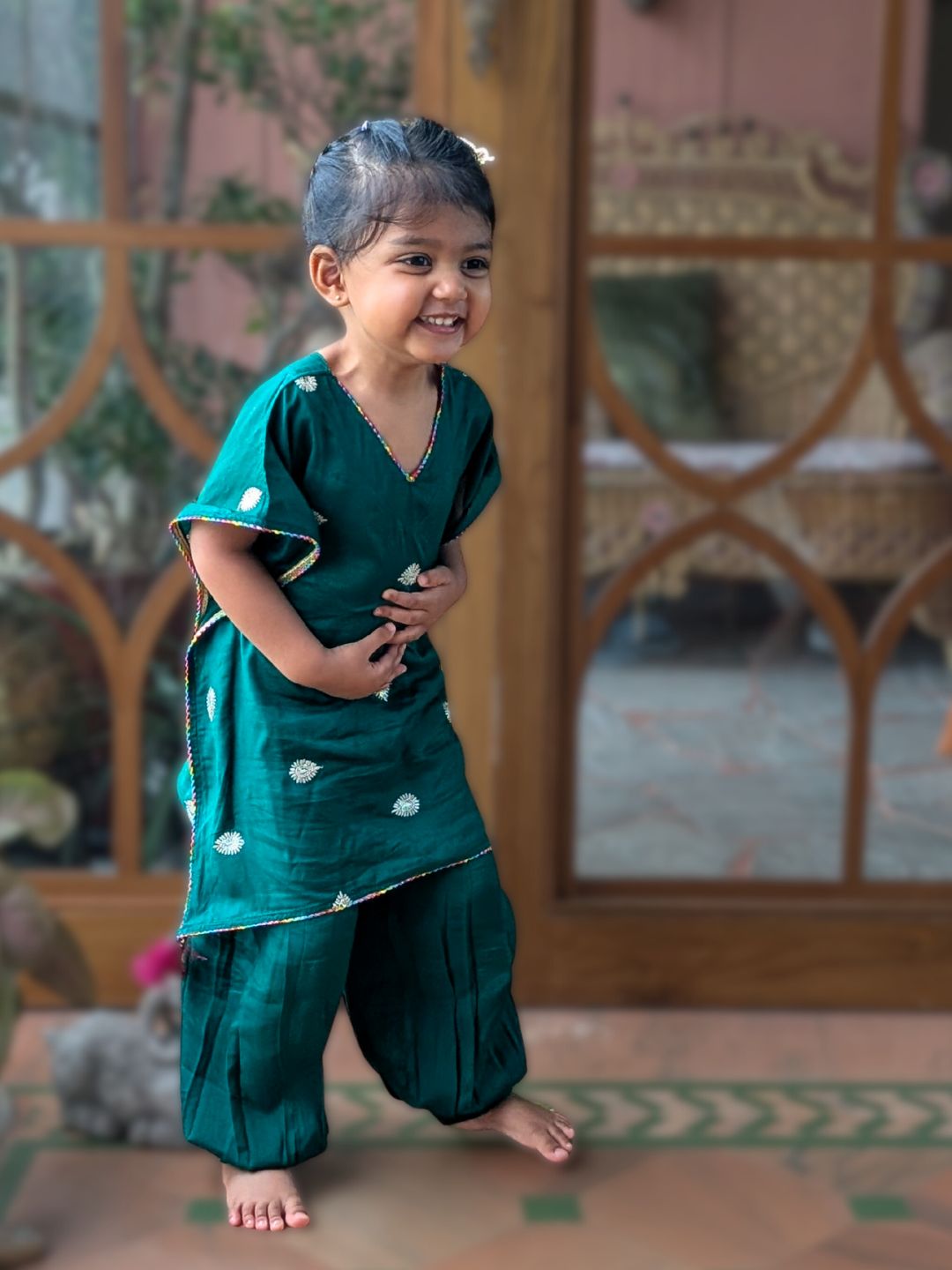 little girl in an emerald green embroidered kaftan with afghan pants