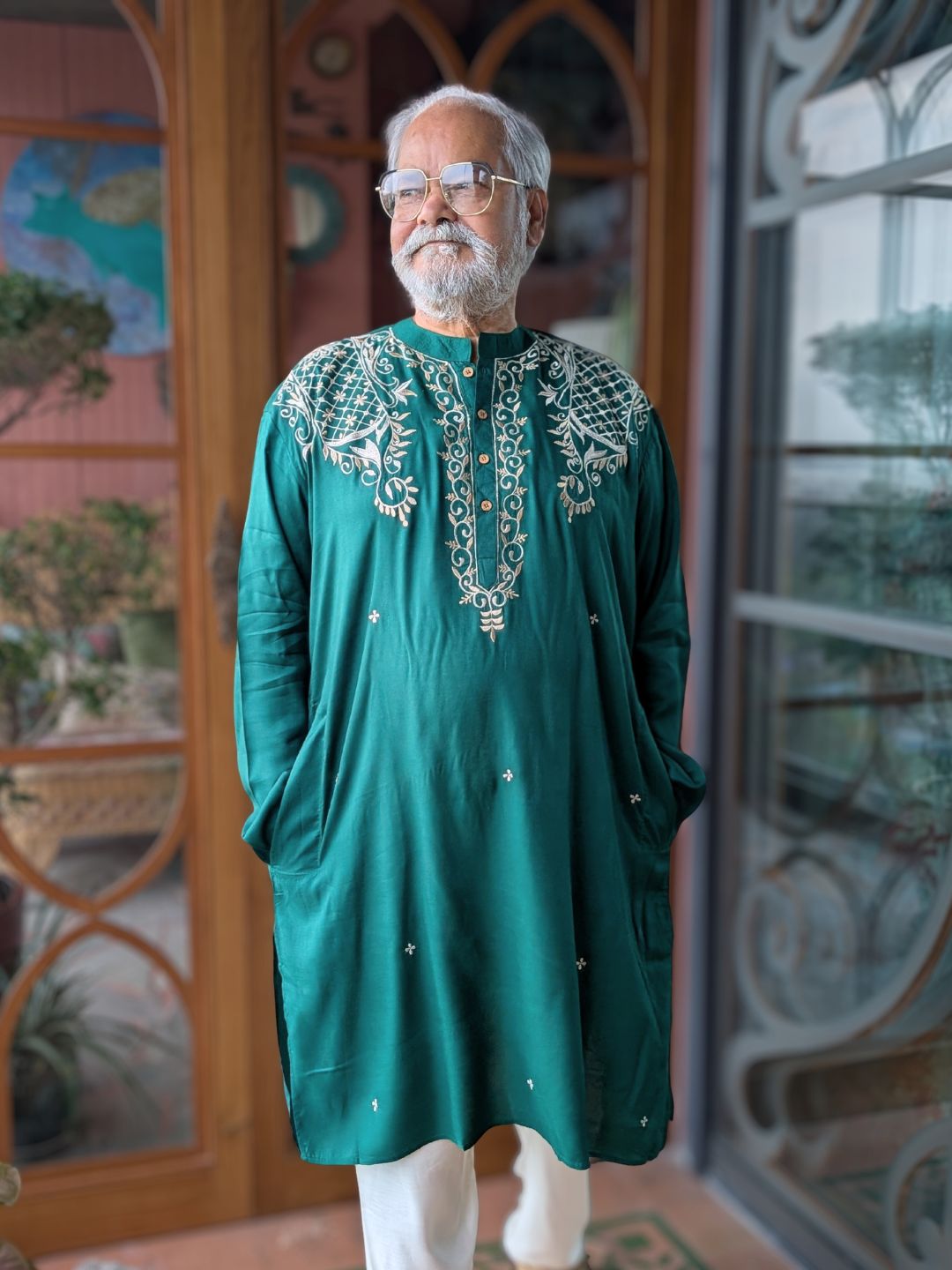 Man wearing a green embroidered kurta standing in front of a decorative door.