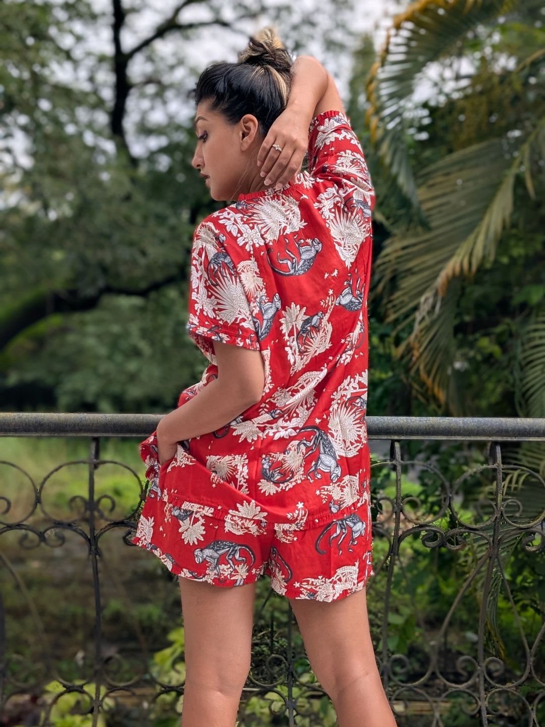 Person wearing a red floral pajama set standing outdoors with greenery in the background