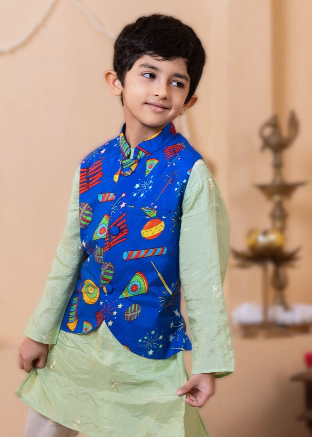 Child wearing a colorful traditional outfit with a blue nehru jacket with diwali fireworks print