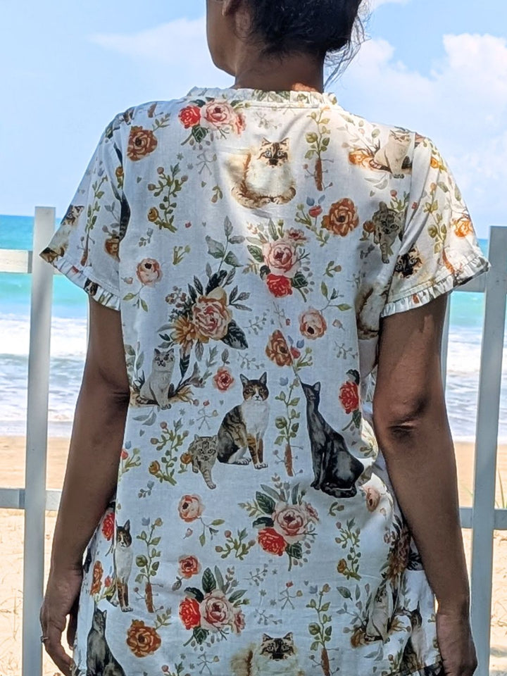 Person wearing a floral and cat-patterned cotton shirt by the beach