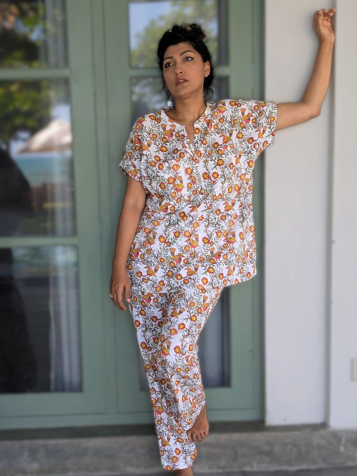 Woman wearing a floral no bra nightsuit loungewear standing against a building.