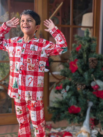 Child wearing red and white Christmas-themed pajamas with a decorated tree in the background.