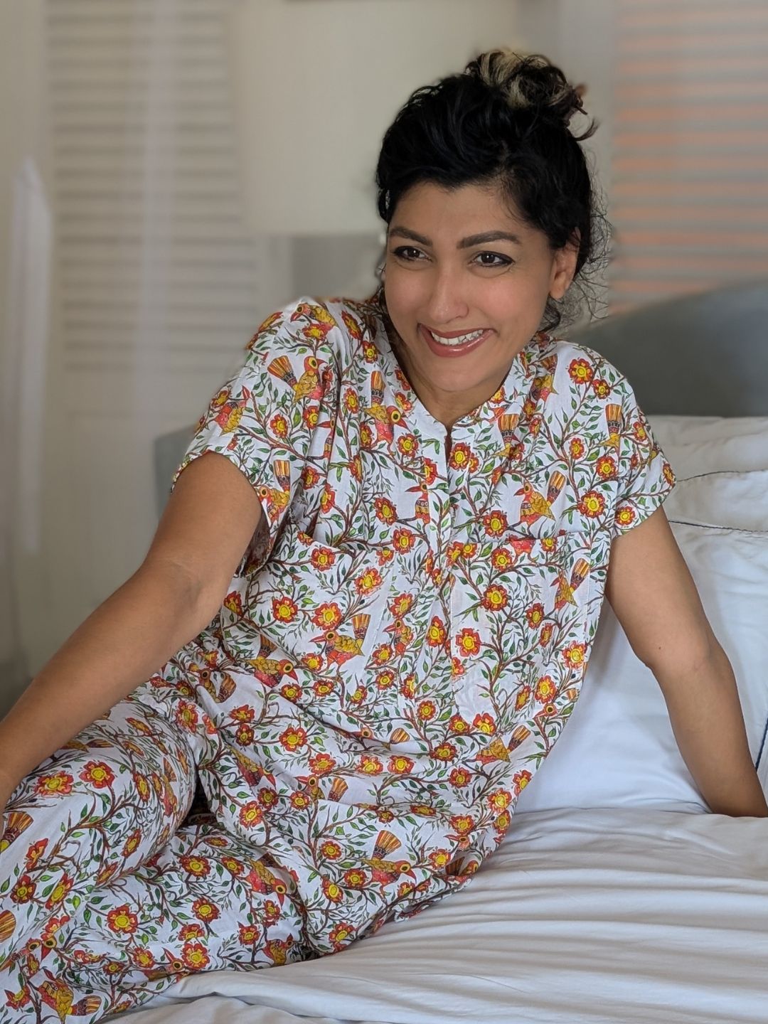 Woman wearing a cotton pajama set sitting on a bed.