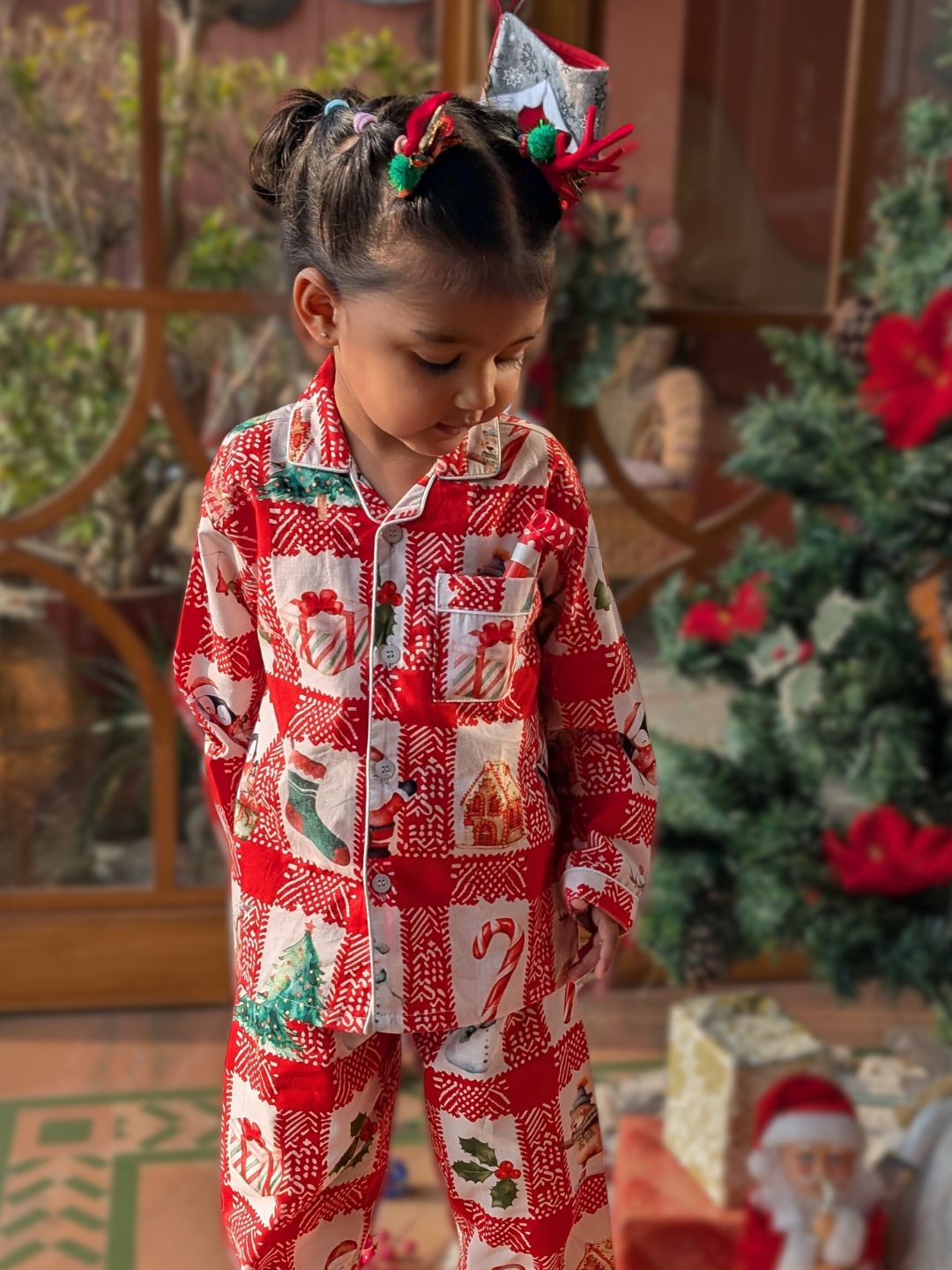 Child wearing a red and white Christmas-themed pajama set with a festive background.