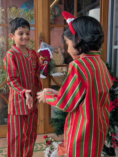 Two children wearing red and green striped pajamas in a festive setting.