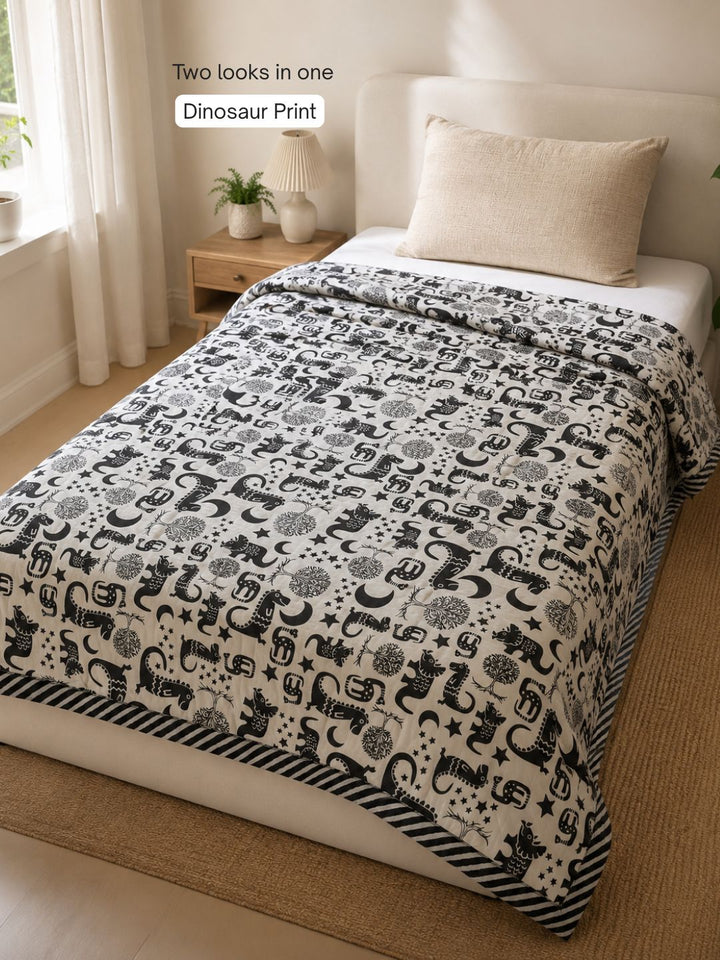 Dinosaur side of Tura Turi reversible muslin blanket - black folk-art dinosaurs, trees, moons and stars on cream cotton