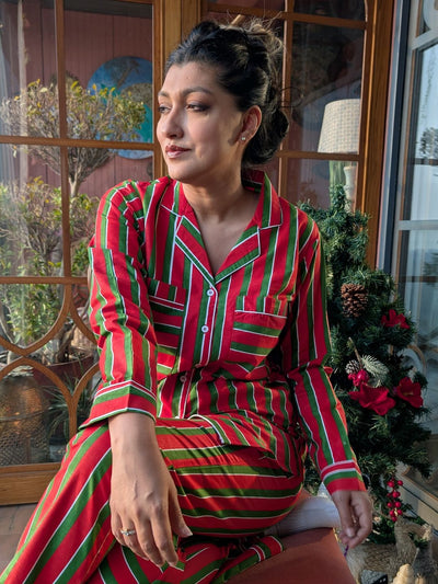 Woman wearing a red and green striped outfit sitting in a room with decorative elements.