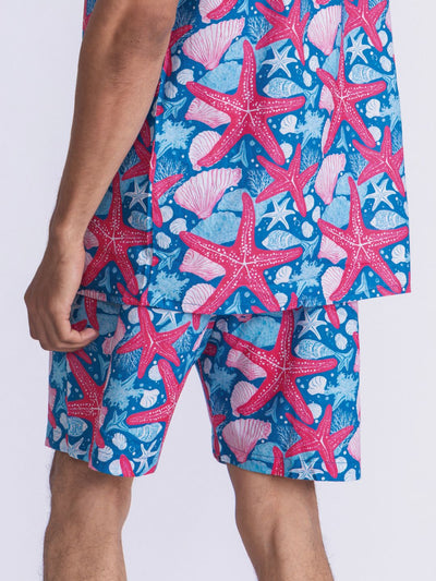 Person wearing blue shorts with starfish and shell design on a white background