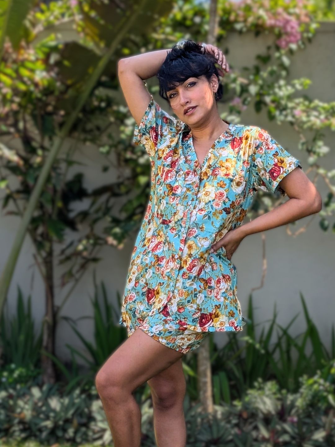 Woman in a floral no bra shorts set posing outdoors with greenery in the background