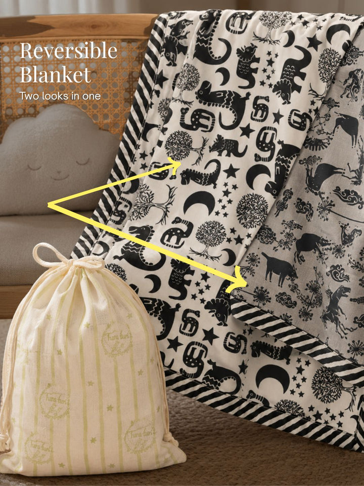 Tura Turi kids cotton muslin blanket folded for gifting, showing the reversible dinosaur and farm-animal prints, 58x90 inches