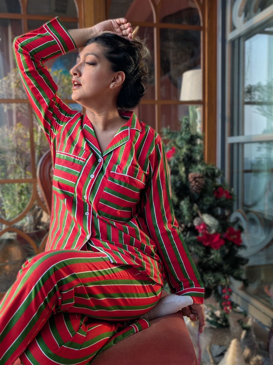 Woman wearing a red and green striped pajama set in a festive indoor setting.