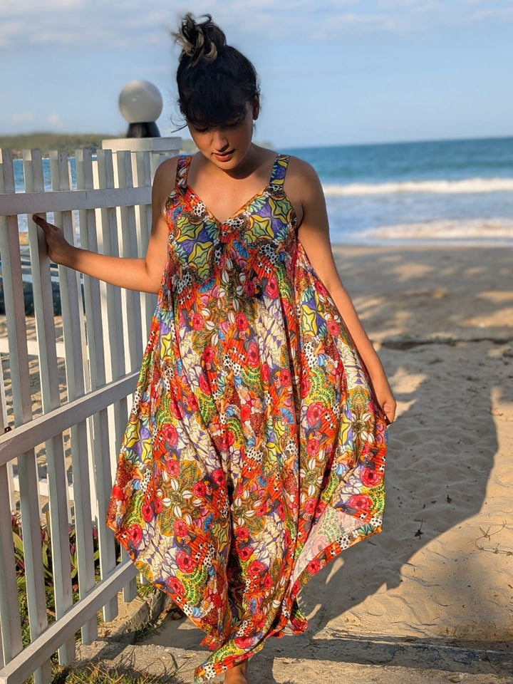 Woman in a colorful kaleidoscope bohemian print jumpsuit standing on a beach.