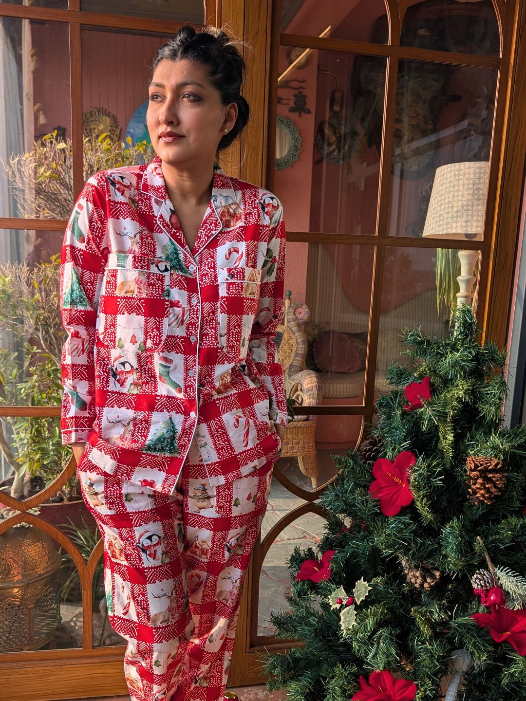 woman wearing a red and white checkered christmas themed nightsuit pajama set set in front of a decorated Christmas tree.