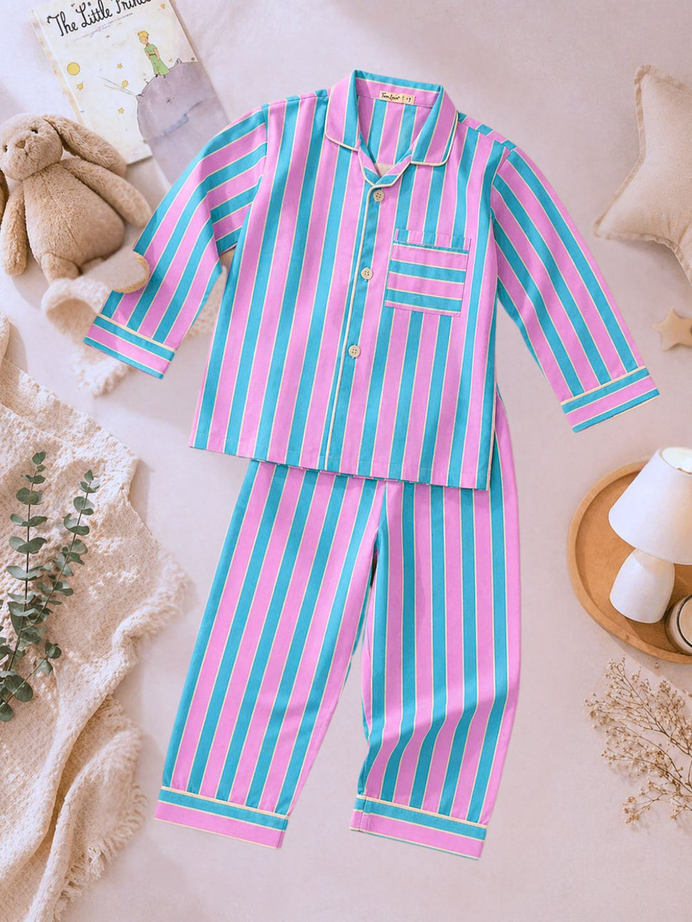 Pink and blue soft cotton striped pajama set on a light background with decorative items.