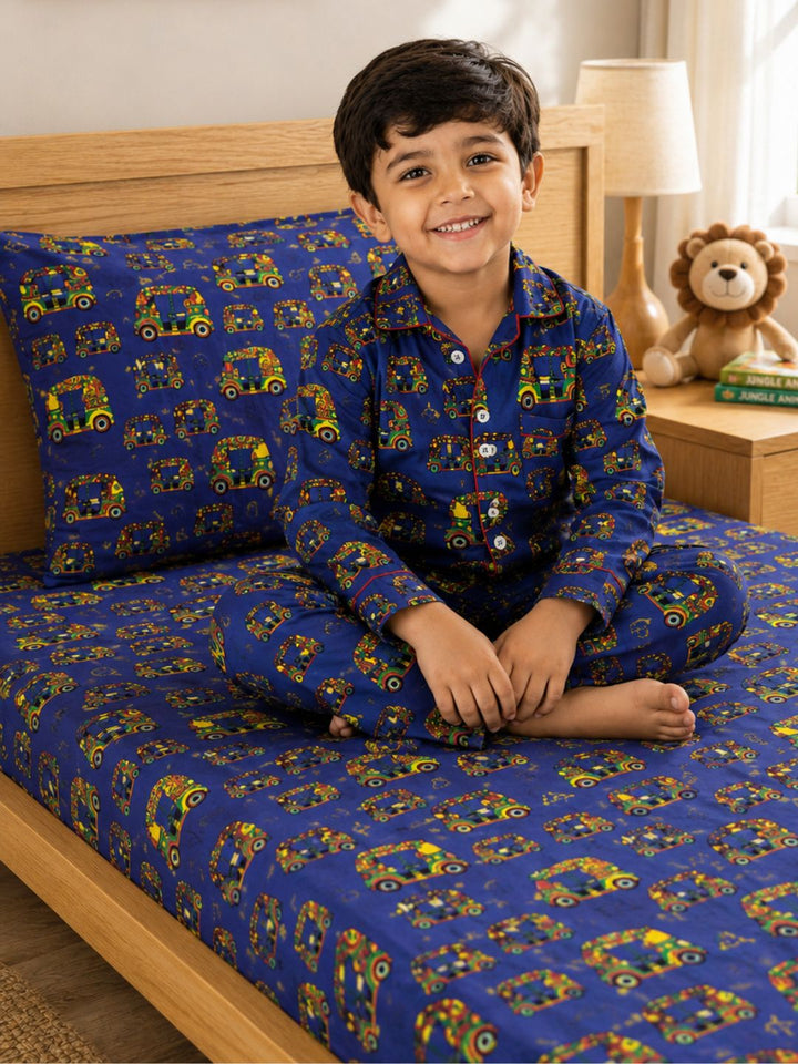 Child wearing a blue vehicle theme pajama set with matching vehicle patterns bedsheet and pillow set.