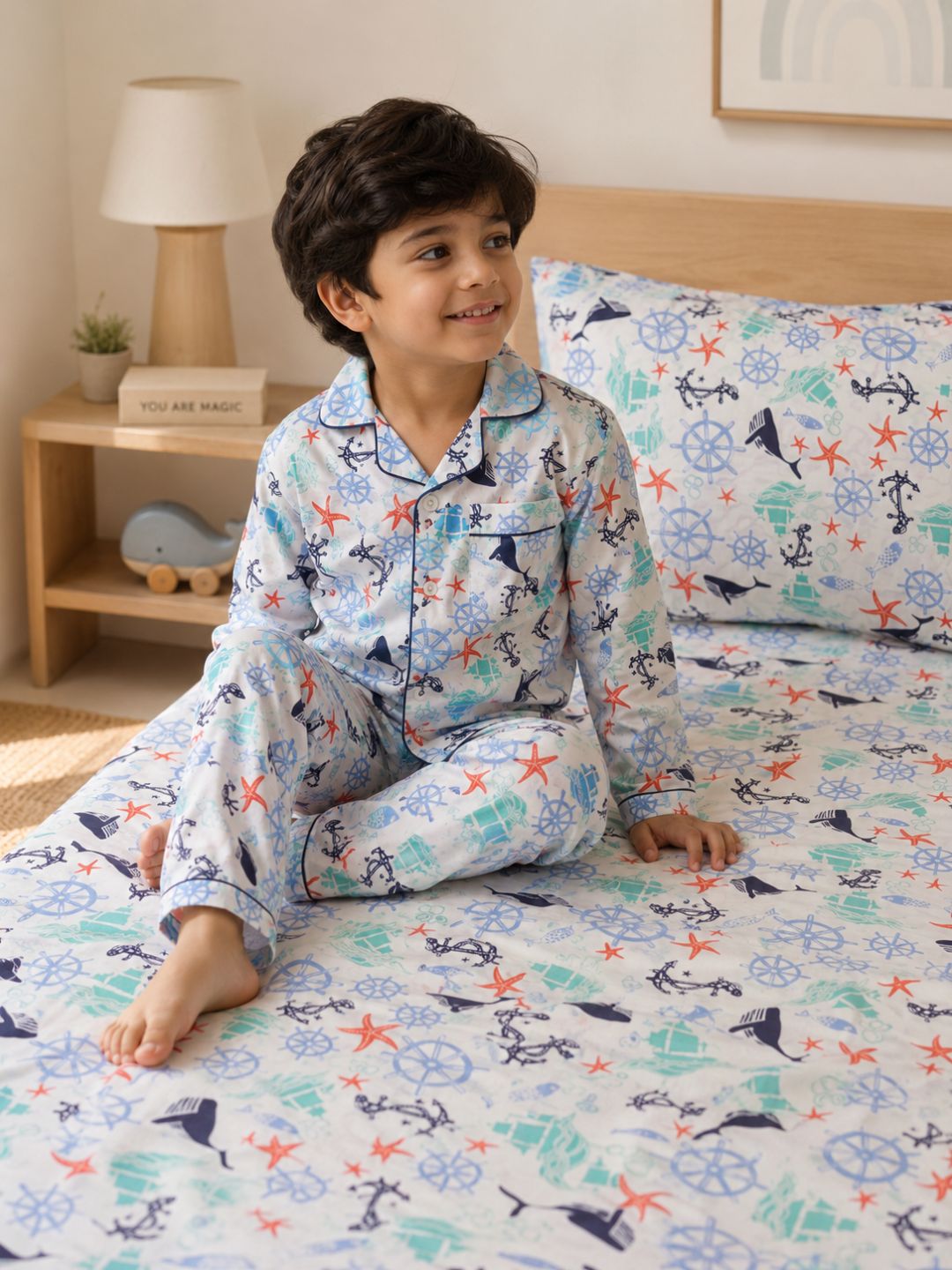 Premium kids nautical bedding set with ocean themed motifs with child wearing matching nightsuit pajama set