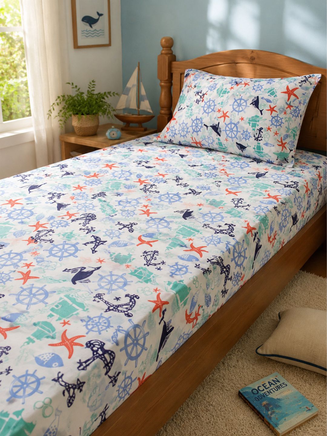 Nautical print cotton bedsheet for kids with matching pillow cover, featuring anchors, whales, starfish and ship wheels on a single bed.