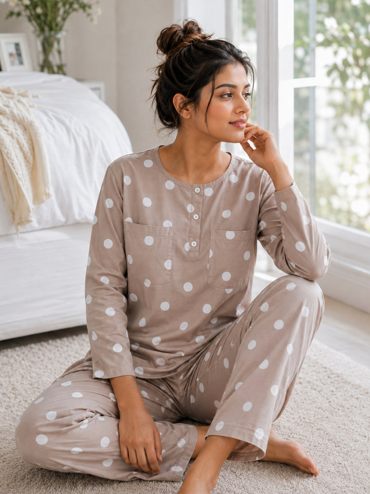 Woman sitting by a sunlit window in a Tura Turi mocha polka dot cotton night suit – long-sleeve tunic top and pyjama set, front view