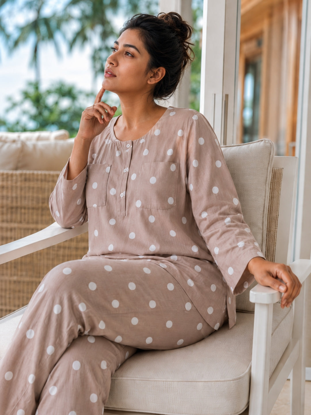 Woman relaxing on a chair in a Tura Turi mocha polka dot cotton night suit, close view of the button placket and two chest pockets