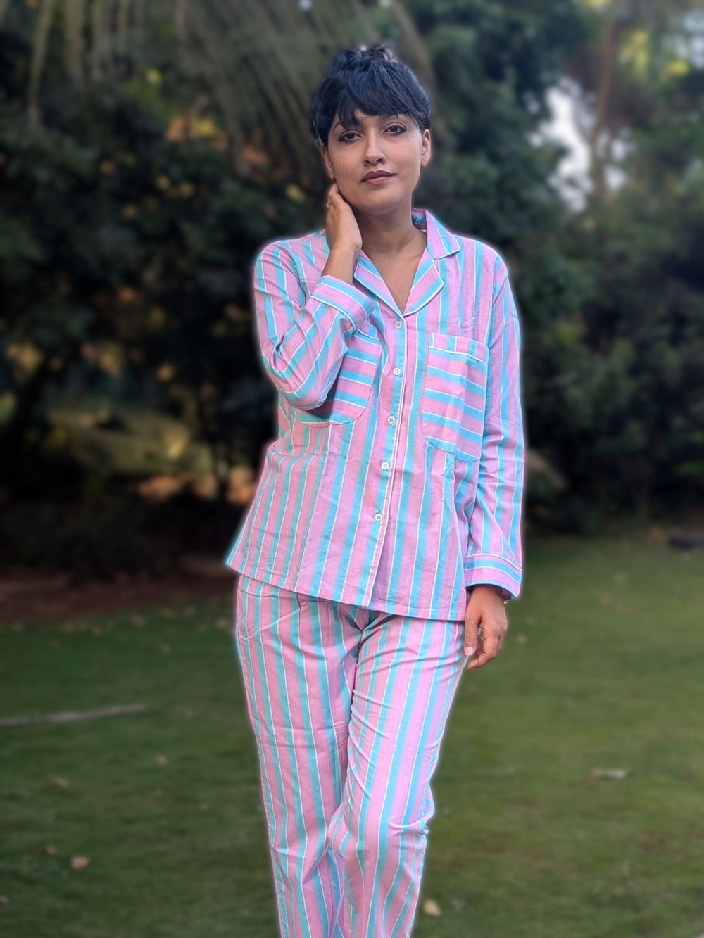 woman wearing breathable cotton pink and blue pinstripe no bra nightsuit pajama set standing in garden