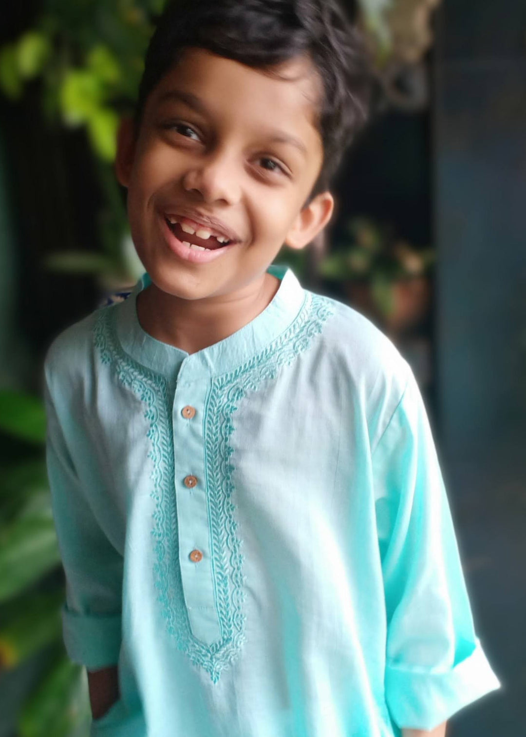 A smiling child wearing a sky blue embroidered cotton malmal kurta