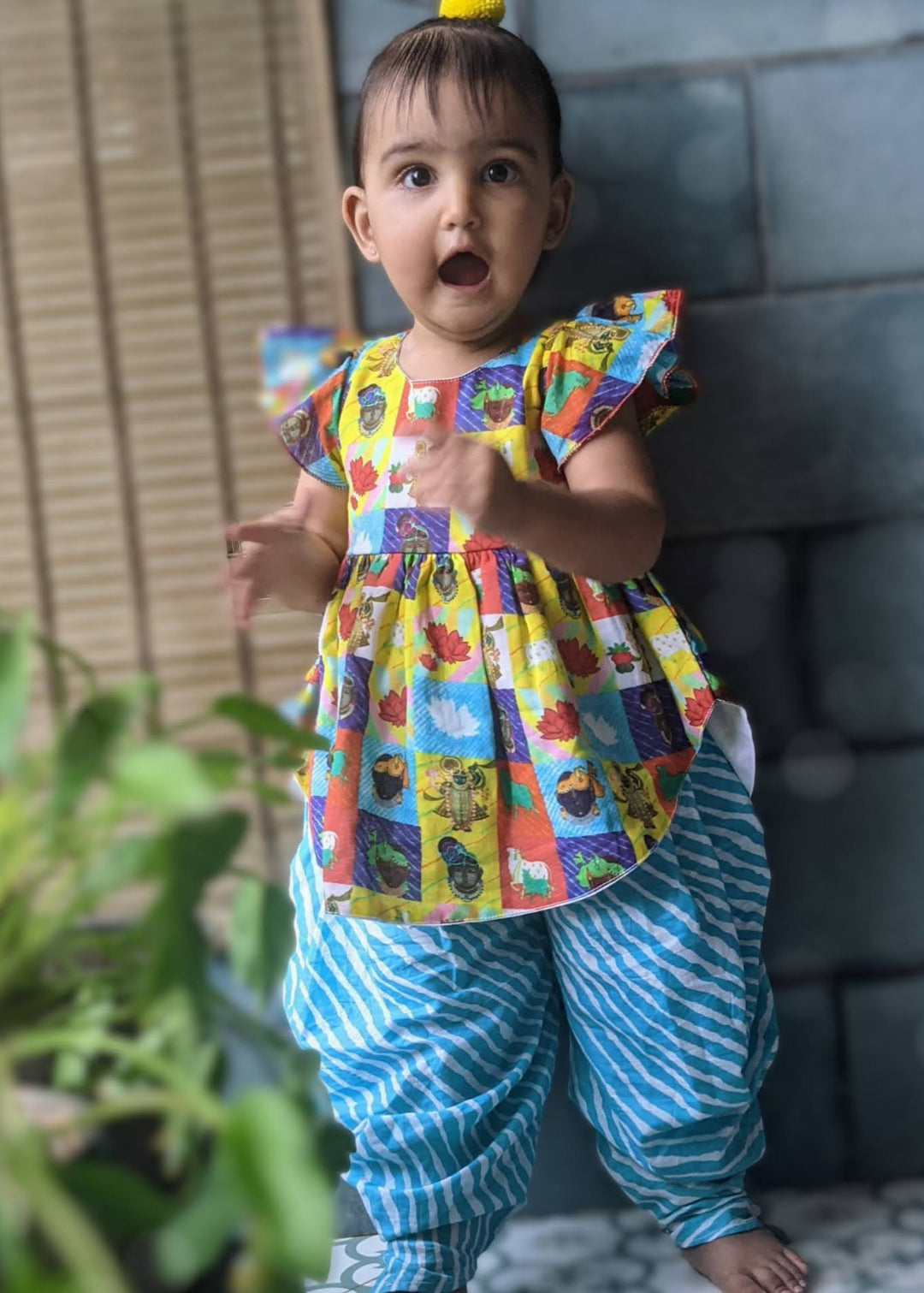 little girl wearing a janamashtami themed pichwai art inspired kurta set in a combination of yellow and blue
