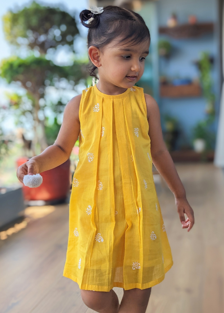 GIRL wearing a yellow cotton dress with white motifs 